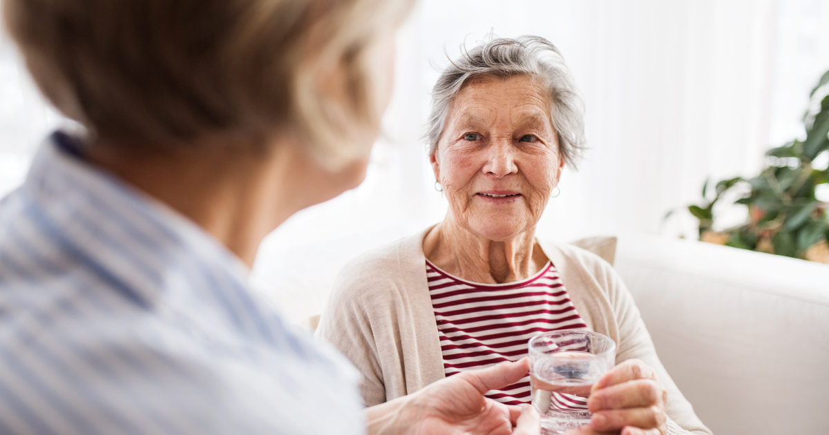 An older woman drinking water to get ready for cataract surgery.