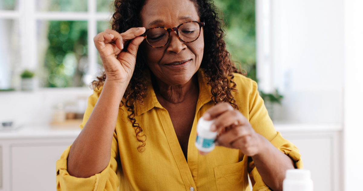 An older woman trying to read the label of her medicine bottle for her chronic condition.