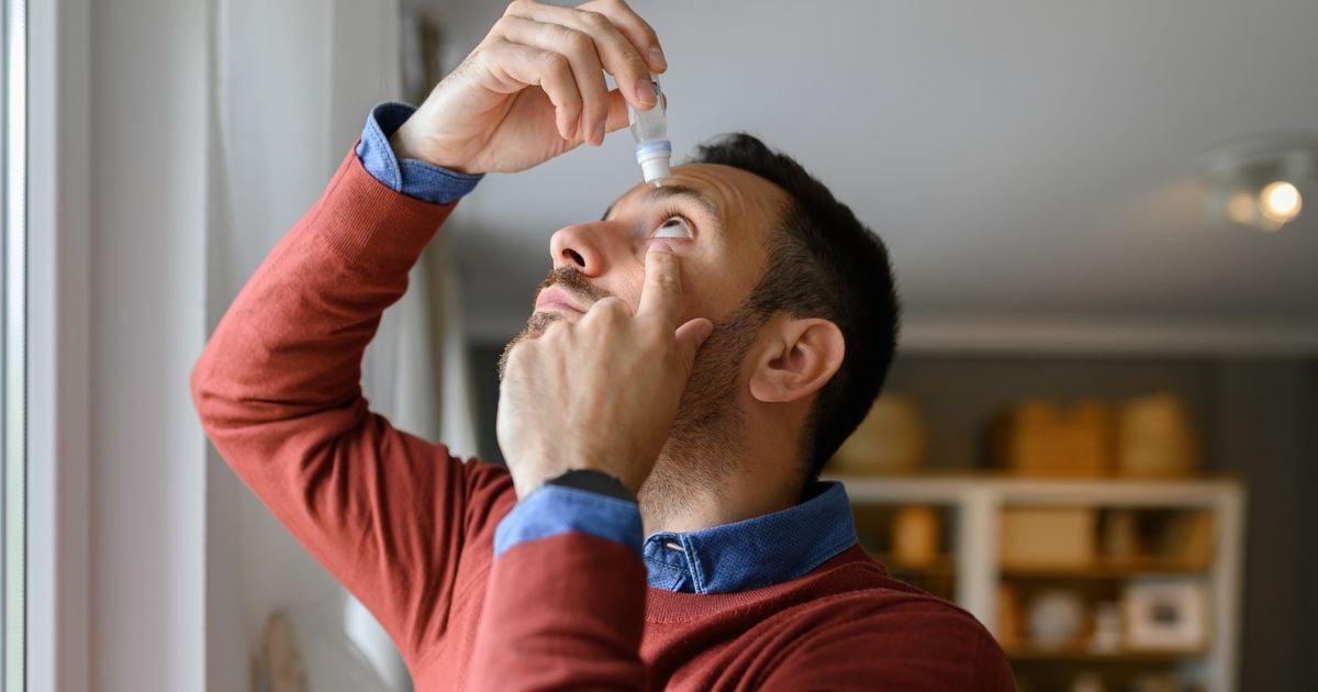 A man using eye drops to help with his dry eye symptoms.