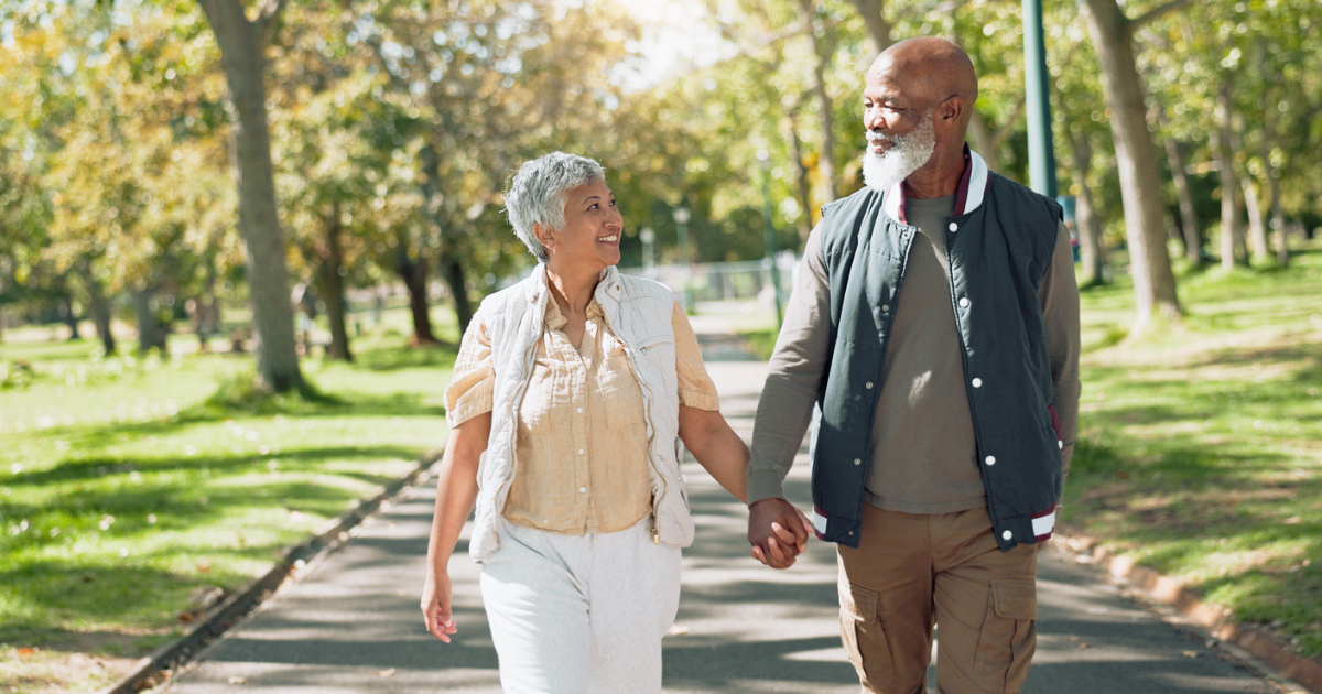 A mature couple holding hands walking outside after light adjustable lens surgery.