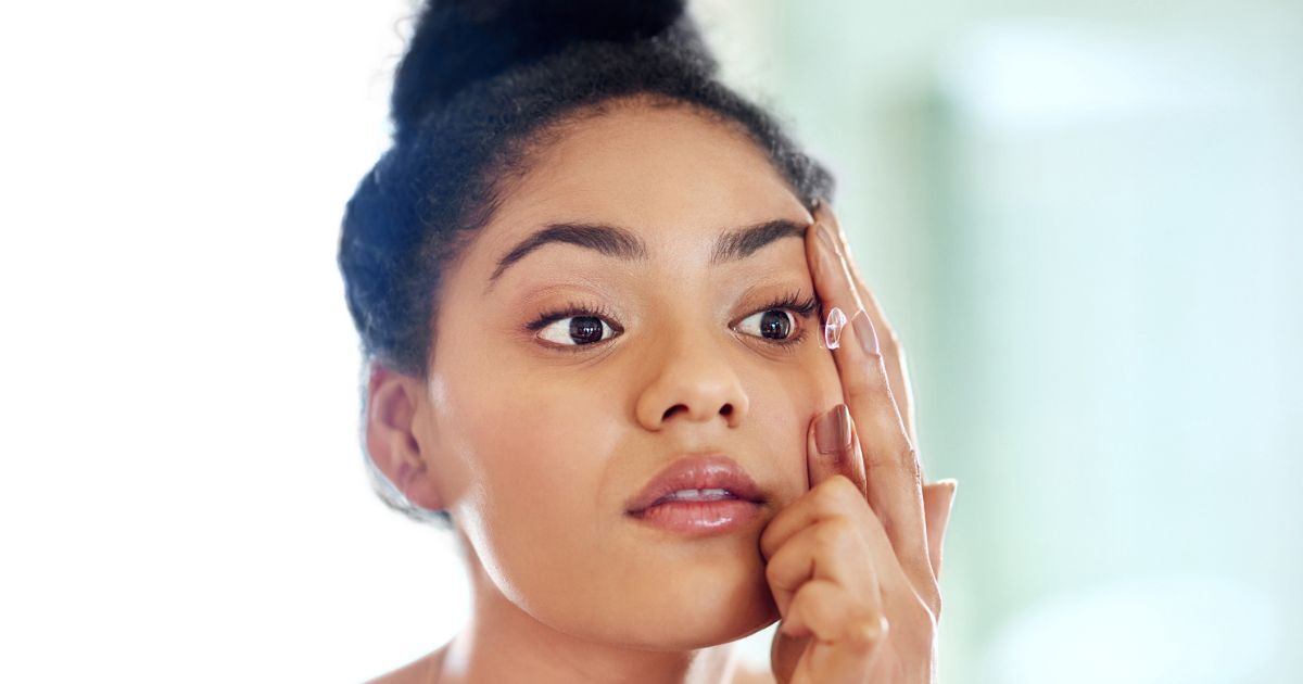 A woman with dry eyes, putting in a contact lens.