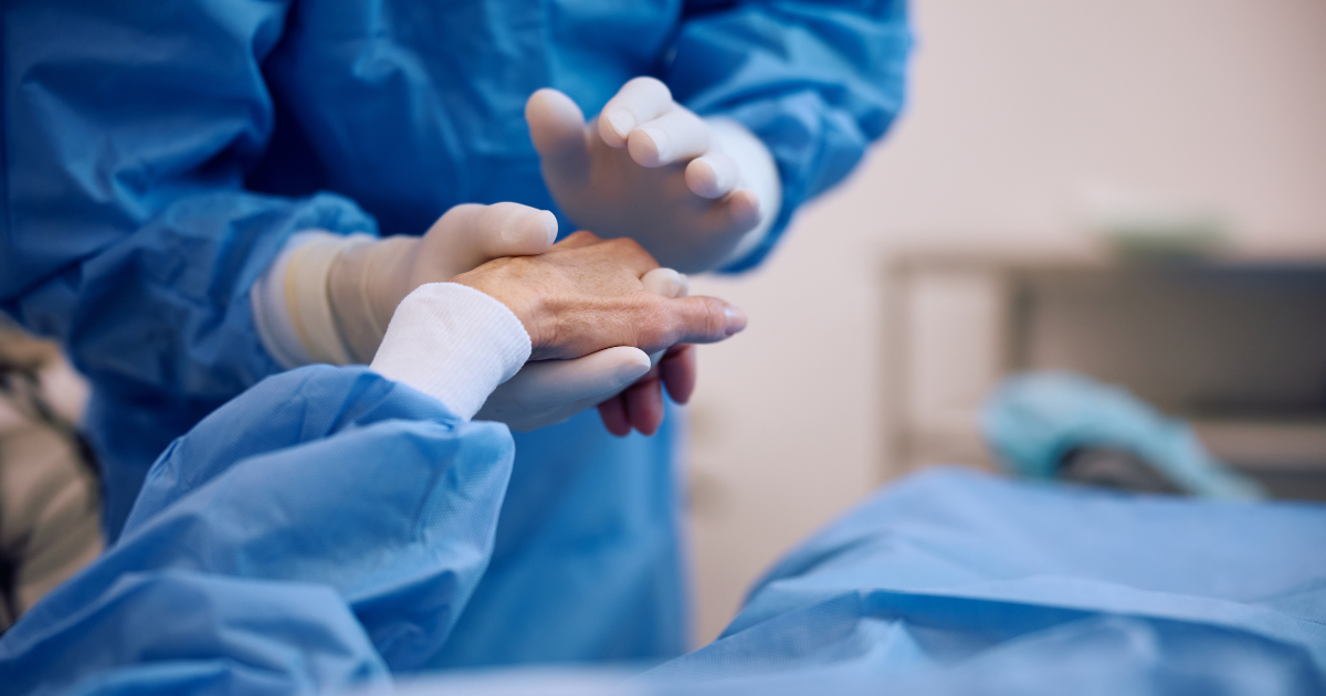 An eye doctor patting the hand of her cataract surgery patient.
