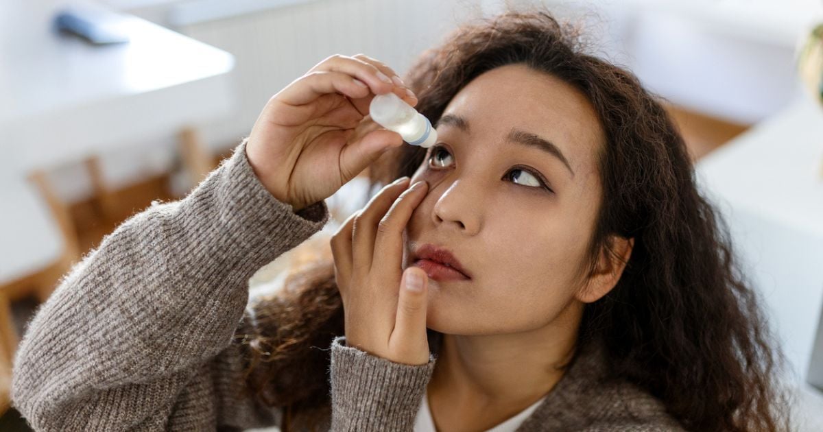 A woman using eye drops to treat her dry eyes and MGD.