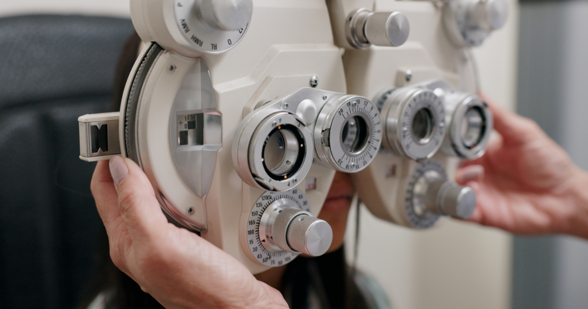 An eye doctor adjusting an eye machine during an eye exam.