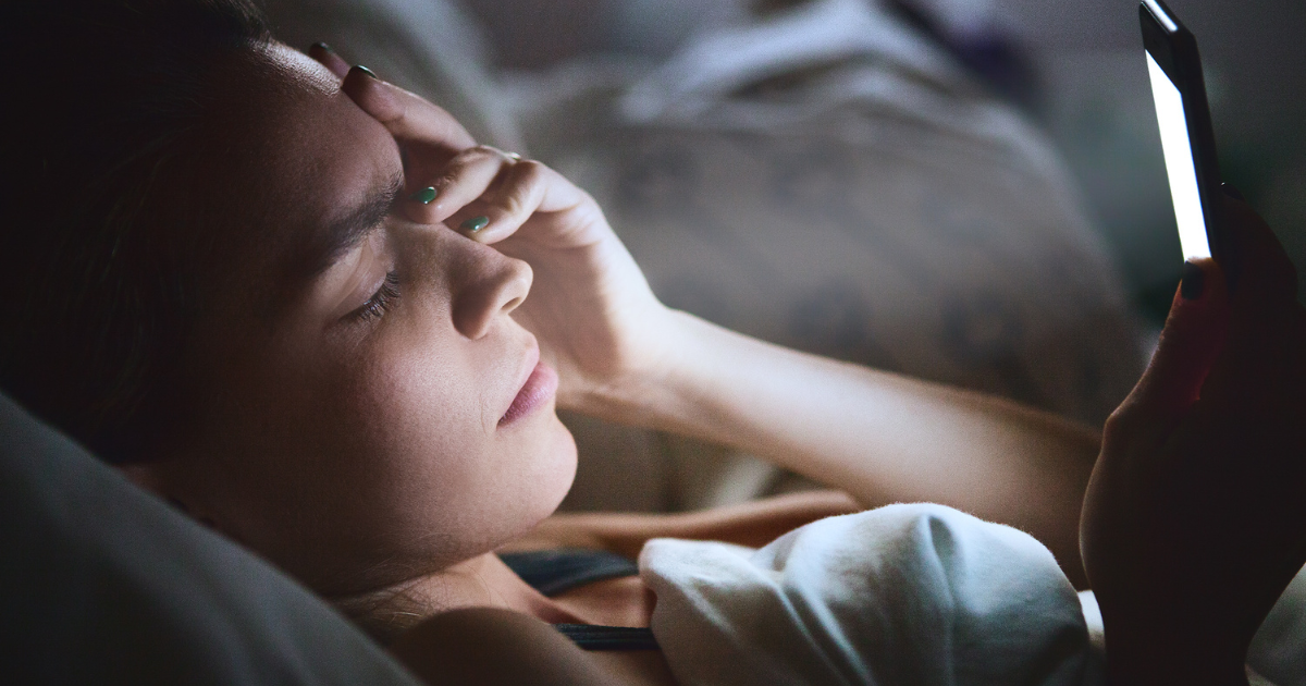 A woman lying in bed rubbing her eye.