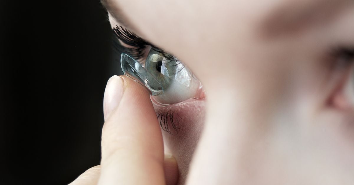A woman putting a contact lens in her eye.