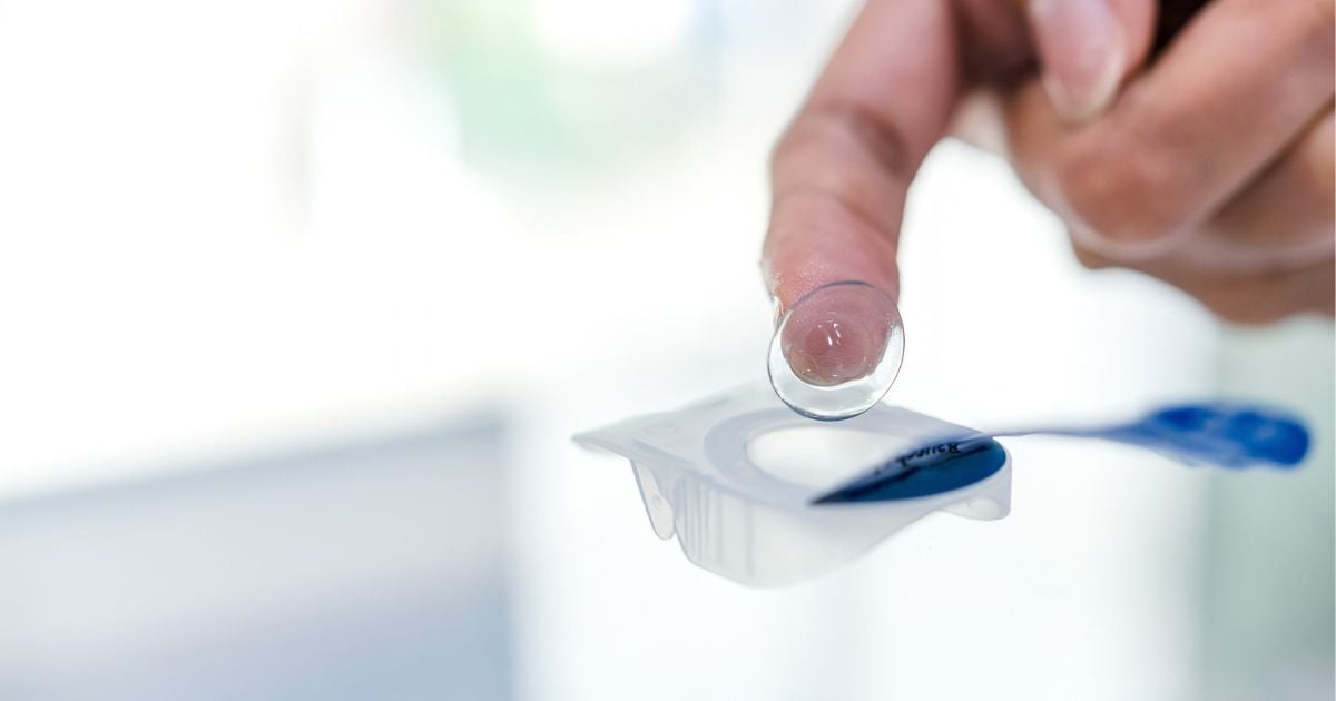 A close up of a finger taking a contact lens out of its case.
