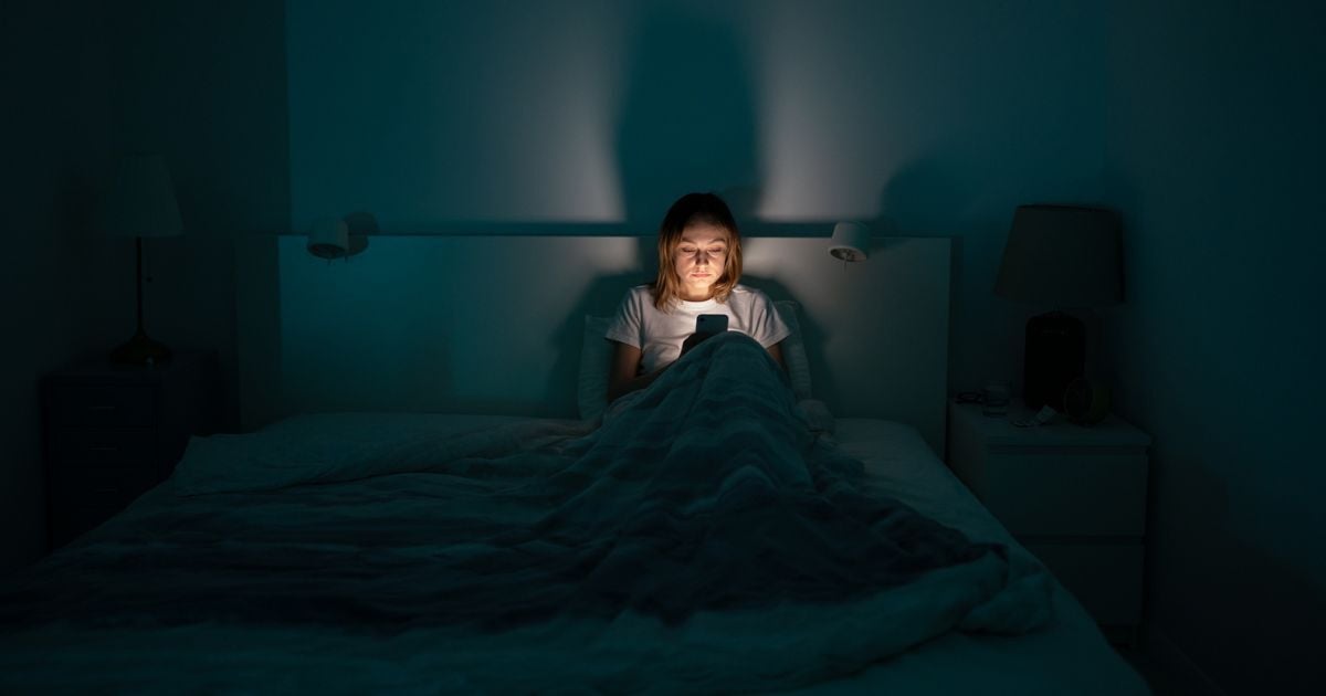 A woman using her smartphone in bed.