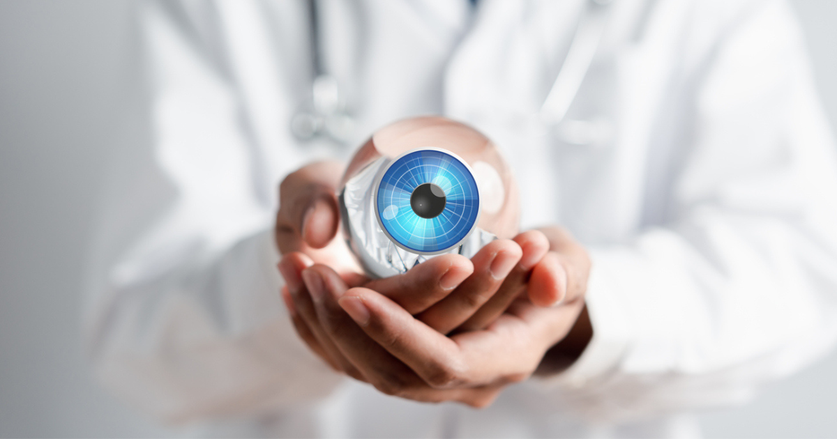 An eye doctor holding a large fake blue eye in his hands.
