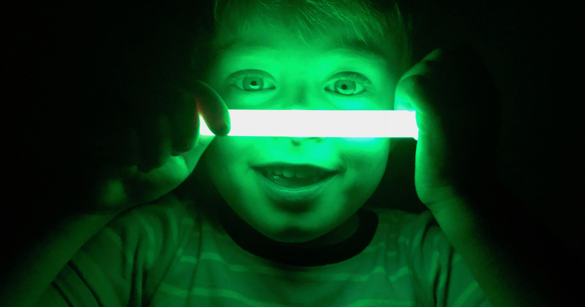 A young boy using a glow stick instead of fireworks.
