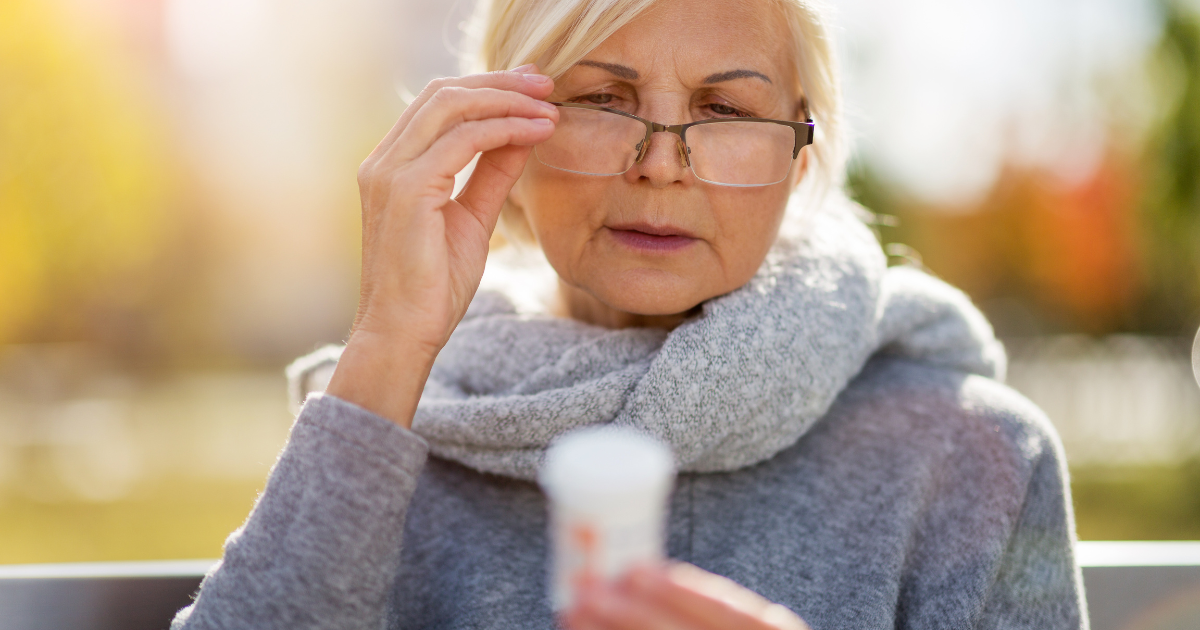 An older woman trying to read her medicine but struggling because of presbyopia.