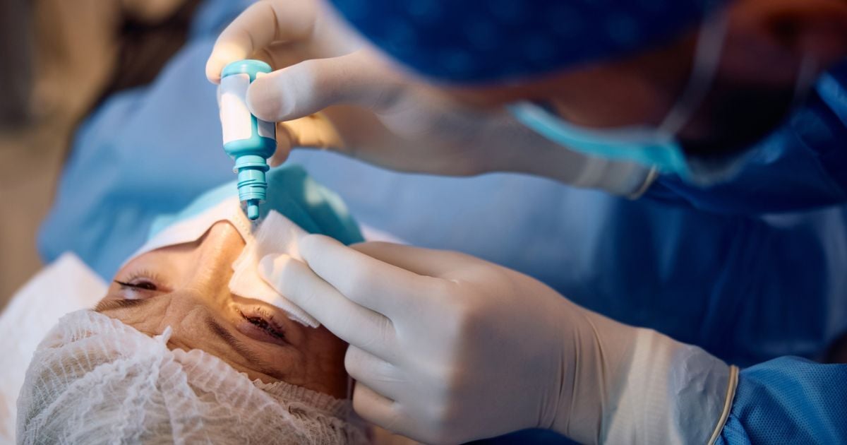 A woman having eye drops put in her eye during glaucoma eye surgery.