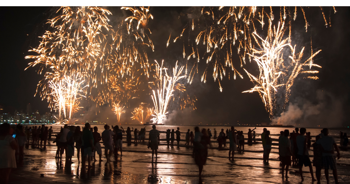 People at a beach watching a fireworks show.