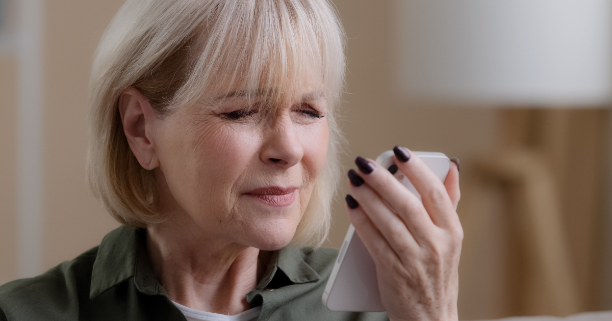 An older woman having trouble reading her phone because of macular degeneration.