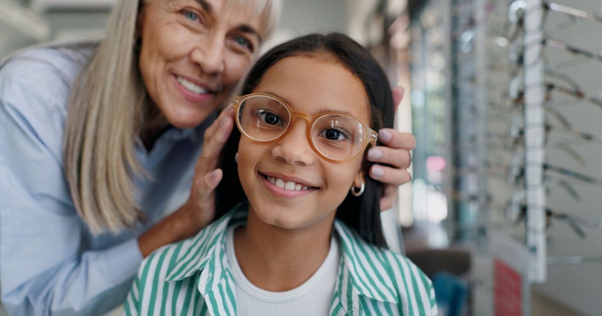 A young girl tries on glasses at the eye doctor's office.