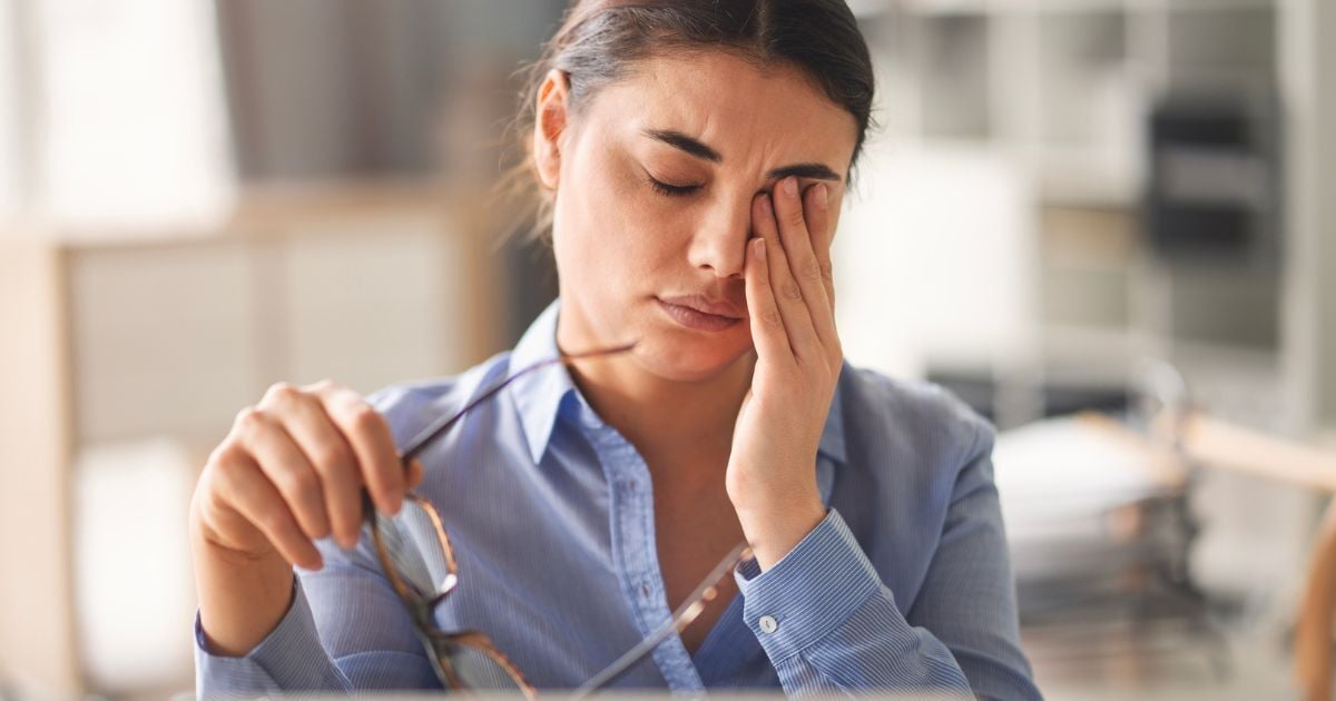 A woman rubbing her eyes because her dry eye is bothering her.